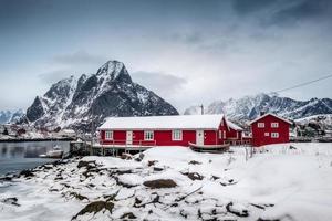 Snowfall on red house with harbor in valley on arctic ocean photo