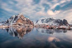 Mountain range reflection on arctic ocean with scandinavian village on winter photo