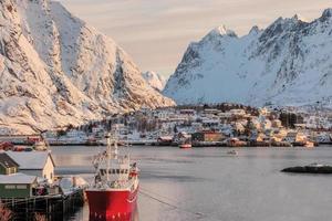 Fishing boat on pier with scandinavian village on Lofoten island photo