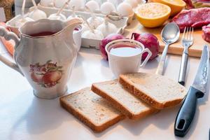 preparar pan con taza de té y utensilios de cocina, egetable y carne en la mesa foto