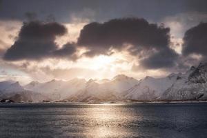 Snow mountain range with cloudy and sunlight shining on coastline