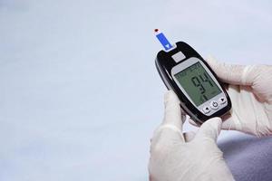 Doctor wear gloves is checking blood sugar level with glucose meter. photo