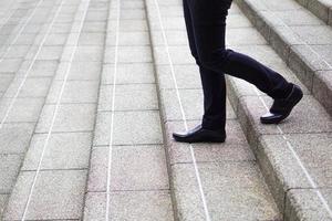 Modern businessman legs walking down the stairs. Concept of business investment decision. photo