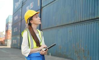 capataz femenina revisando contenedores para enviar en el puerto terminal. foto