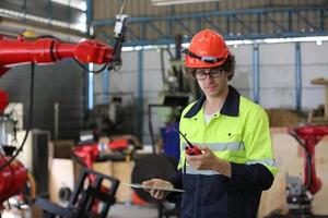 Professional industrial factory employee working with machine part, checking and testing industrial equipment and robot arms in large Electric electronics wire and cable manufacturing plant factory photo