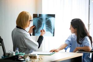 Female doctor show image of xray film to female patient and explain to her. photo