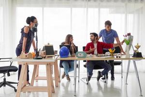 Diverse group of young business people discussing a work project while sitting together at a table in a modern office. coworking concept photo