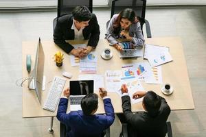 Top view of group of multiethnic busy people working in an office, Aerial view with businessman and businesswoman sitting around a conference table with copy space, Business meeting concept. photo