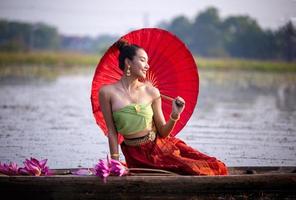 jóvenes asiáticas con vestimenta tradicional en el bote y flores de loto rosa en el estanque.hermosas chicas con traje tradicional.chica tailandesa con vestido retro tailandés, chica tailandesa con traje tradicional foto