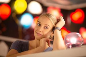 retrato de mujer sonriendo de pie contra la colorida luz bokeh foto