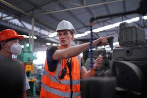 los ingenieros de mantenimiento están trabajando frente a la reparación automatizada de maquinaria cnc en una lista de verificación de mantenimiento en la línea de producción. foto