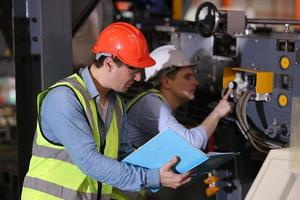 Men industrial engineer wearing a safety helmet while standing in a heavy industrial factory. The Maintenance looking of working at industrial machinery and check security system setup in factory. photo