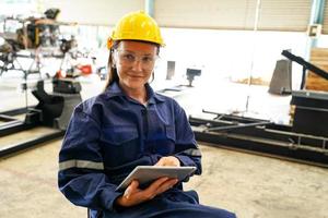 Professional young industrial factory woman employee working with machine part, checking and testing industrial equipment and robot arms in large Electric electronics wire and manufacturing plant photo
