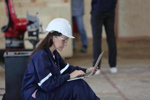 ingeniero industrial o trabajador con casco mientras está de pie en una fábrica industrial pesada. el mantenimiento que busca trabajar en maquinaria industrial y verificar la configuración del sistema de seguridad en fábrica. foto