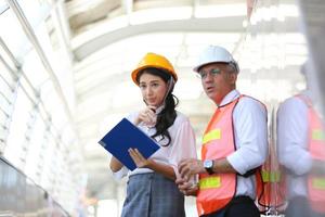 el ingeniero y la mujer de negocios revisando el portapapeles en el edificio del sitio de construcción. el concepto de ingeniería, construcción, vida urbana y futuro. foto