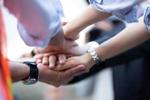 Stack of hands. Unity and teamwork concept. Close up top view of young business people putting their hands together photo