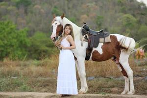 mujer joven con su caballo en la luz del atardecer. fotografía al aire libre con una modelo de moda. estado de ánimo de estilo de vida foto