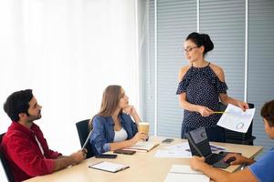 Diverse group of young business people discussing a work project while sitting together at a table in a modern office. coworking concept photo