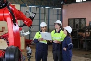 hree Diverse Multicultural Heavy Industry Engineers and Workers in Uniform check automatics robot arm for Factory Using. Female Industrial Contractor is Using a Tablet Computer.