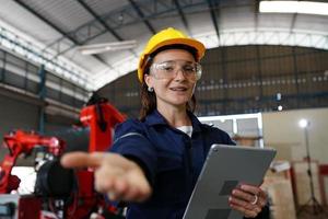 Professional young industrial factory woman employee working with machine part, checking and testing industrial equipment and robot arms in large Electric electronics wire and manufacturing plant photo