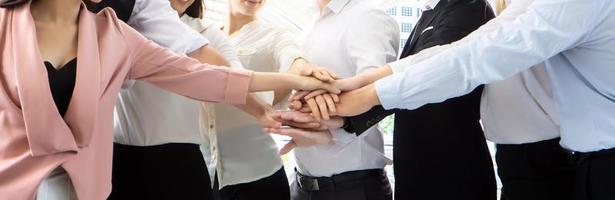 Stack of hands. Unity and teamwork concept. Close up top view of young business people putting their hands together photo