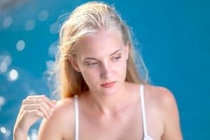 mujer en bikini blanco bronceándose junto a la piscina foto