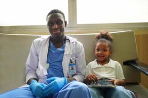 Black skin doctor checking up kid body in clinic. photo