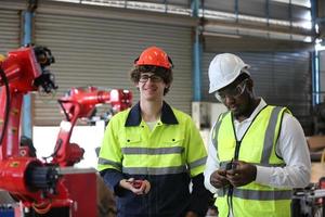 Diverse Multicultural Heavy Industry Engineers and Workers in Uniform check automatics robot arm for Factory Using. Female Industrial Contractor is Using a Tablet Computer. photo