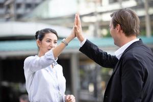 gente de negocios al aire libre. un apuesto hombre de negocios y su hermosa colega discutiendo un nuevo proyecto mientras cruzan la calle, antecedentes urbanos foto