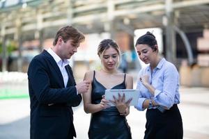 Businessman and women looking on tablet  against building, Business people discussing and smiling while walking together outdoor photo