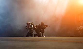 siluetas de soldados del ejército en la niebla contra una puesta de sol, equipo de marines en acción, rodeado de fuego y humo, disparando con rifle de asalto y ametralladora, atacando al enemigo