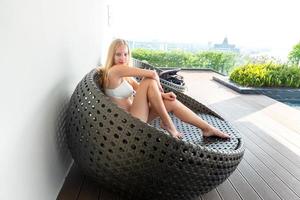 Young woman enjoying and relaxing at poolside. Slim young girl model in white bikini  by the pool. photo