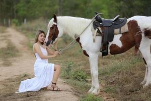 mujer joven con su caballo en la luz del atardecer. fotografía al aire libre con una modelo de moda. estado de ánimo de estilo de vida foto