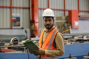 el capataz de los trabajadores de la industria o el trabajo de los trabajadores en el sitio de la fábrica revisan la máquina o los productos en el sitio. ingeniero o técnico revisando material o máquina en planta. industrial y fábrica. foto