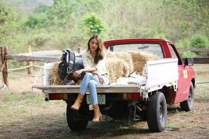 modelo de vaquera posando en la granja. un retrato de una hermosa joven vaquera apoyada contra una pared en un establo en la granja. foto