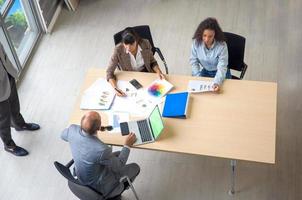 Diverse business colleagues sitting at a desk in a modern office talking together over a laptop photo