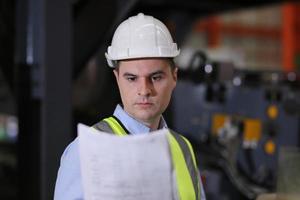 el capataz de los trabajadores de la industria o el trabajo de los trabajadores en el sitio de la fábrica revisan la máquina o los productos en el sitio. ingeniero o técnico revisando material o máquina en planta. industrial y fábrica. foto