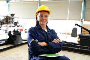 Professional young industrial factory woman employee working with machine part, checking and testing industrial equipment and robot arms in large Electric electronics wire and manufacturing plant photo