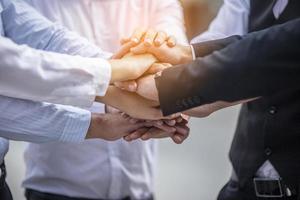 Stack of hands. Unity and teamwork concept. Close up top view of young business people putting their hands together photo