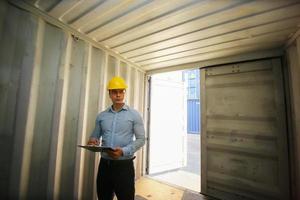 Foreman control loading Containers box from Cargo freight ship for import export. photo