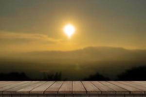 Wooden table and blur of beauty, sunset sky, and mountains as background.