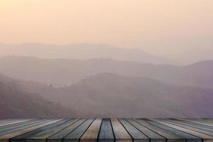 Wooden table and blur of beauty, sunset sky, and mountains as background. photo
