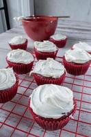 red velvet cupcakes with white icing on red wire rack