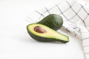 Whole and cut avocados on the table with napkin photo