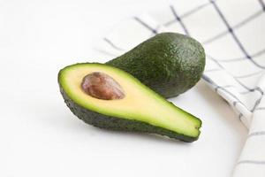 Whole and cut avocados on the table with napkin Close-up photo