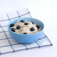 Healthy porridge with blueberries on white table, with blue checkered table cloth under it. Perfect start of the day photo