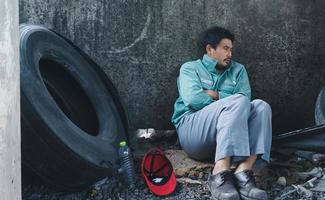 Homeless man sitting sadly beside the wall photo