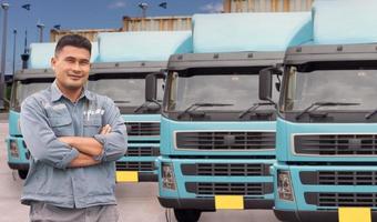 mature Asian man occupation truck driver smiling confident optimistic standing with his arms crossed proud. background semi-truck container transportation delivery shipping park in warehouse at port. photo