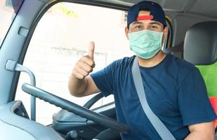 Asian truck driver man wearing mask to protect against dust and the spread of COVID 19 in front of the car. Safety ideas for a worker in the transportation business. And is new normal life. photo