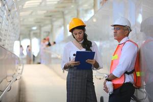 el ingeniero y la mujer de negocios revisando el portapapeles en el edificio del sitio de construcción. el concepto de ingeniería, construcción, vida urbana y futuro. foto